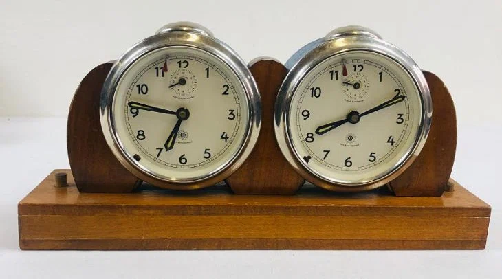 Exacta-family clock with paired round units on a wooden base.